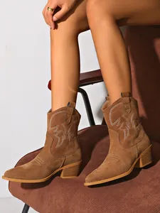 Close-up of women's brown suede western ankle boots with embroidery and block heel
