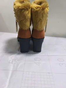 Back view of brown high heel boots with mustard yellow faux fur trim and tassels