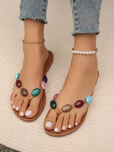 Nahaufnahme von Damen-Flip-Flops mit lebendigen, bunten Steinverzierungen und Perlen