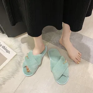 Détail de chaussons en peluche vert menthe à brides croisées portés à la maison