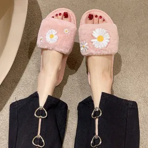 Close-up van roze pluizige pantoffels met open teen en wit madeliefjesborduurwerk