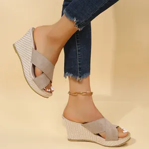 Close-up view of stylish women's beige suede wedge slides with straw-woven heels