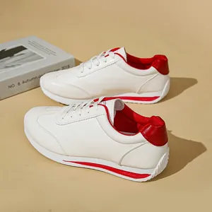 Close-up of white women's casual sneakers with stylish red heel and stripe details.