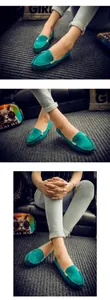 Detalle de mocasines de ante color verde azulado con hebilla dorada usados por un modelo