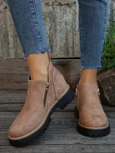 Close-up of khaki suede ankle boots with side zipper and thick rubber sole for women