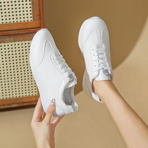 Detailed shot of stylish white athletic sneakers held against a soft beige backdrop
