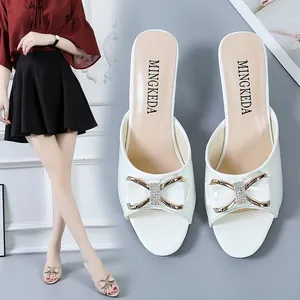 Detailansicht der weißen Peep-Toe Pantoletten mit Schleife und goldener Metallschnalle.
