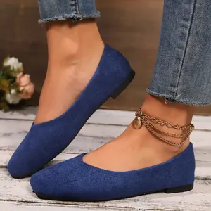 Detailed macro view of blue suede square-toe slip-on flat shoes with rustic wood background