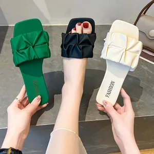 Primer plano detallado de sandalias planas plisadas para mujer en verde y beige