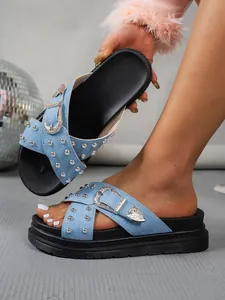 Primer plano de sandalias de plataforma en denim azul claro con tachuelas y hebillas