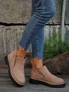 Detail view of stylish women's tan suede ankle boots with side zipper and thick sole