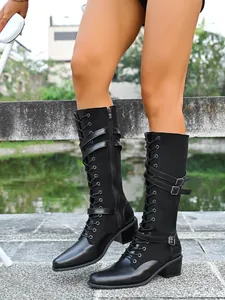 Detailed view of black knee-high knight boots with lace-up front and decorative buckle straps
