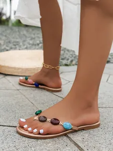 Detailansicht Damen Flache Flip-Flops mit lebhaften, farbenfrohen Steinverzierungen.