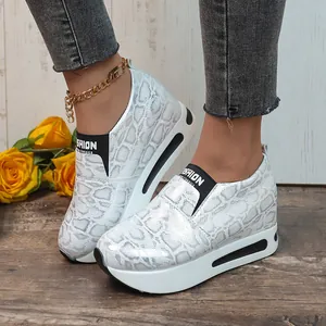 Primo piano di sneakers con zeppa bianche a stampa serpente e suola platform