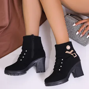 Detail of black high-heel ankle boots with rhinestone accents and elegant pearl buckle