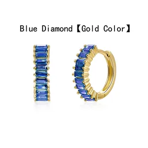 Close-up of golden hoop earrings featuring vibrant blue baguette-cut cubic zirconia.