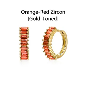 Detail view of gold hoop earrings featuring orange baguette-cut zircon