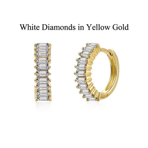 Close-up of elegant gold-finished huggie hoop earrings featuring baguette-cut white zircons