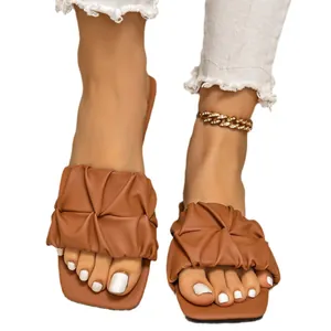 Elegantes sandalias planas de mujer en color marrón plisado para vacaciones de verano y uso diario