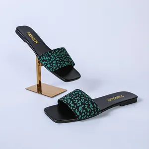 Close-up of square-toe flat slides with green leopard print strap and gold lettering