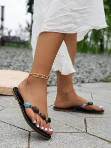 Moderne Damen-Flip-Flops für den Sommer mit bunten Steinakzenten und goldenem Fußkettchen