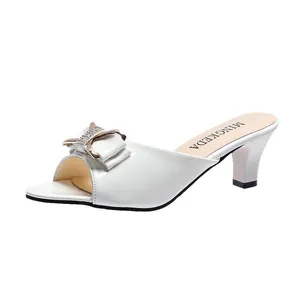 Eleganter weißer Peep-Toe-Mule-Absatz mit dekorativer Schleife und Strass-Schnalle.