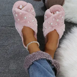 Close-up view of pink fuzzy cross-strap slippers with elegant pearl embellishments.
