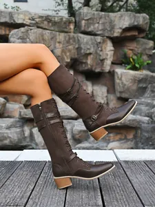 Detailed side view of brown leather knight boots with belt buckles and chunky heels