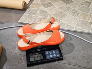 Close-up of lightweight orange peep-toe sandals being weighed at 271.6g