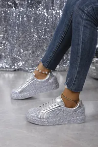Detailed view of silver glitter low-top sneakers featuring a lace-up design and flat sole