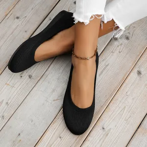 Close-up top view of black knitted ballet flats with round toe on rustic wood background