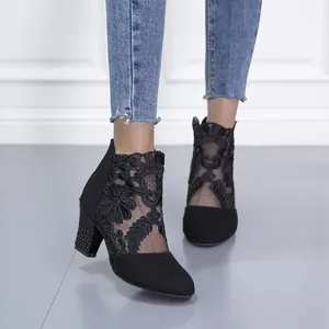 Detail view of stylish black lace mesh high heel ankle boots with studded chunky heels