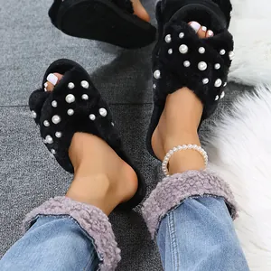 Close-up detail of black fuzzy slippers with elegant pearl accents and cross-band design