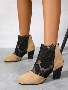 Detailed macro view of elegant black lace mesh and tan suede block heel ankle boots