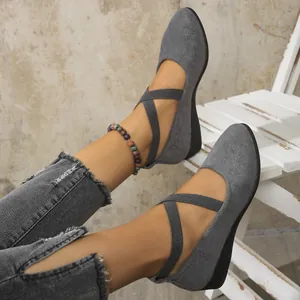 Macro detail view of grey suede pointed-toe wedge shoes with elastic cross straps.