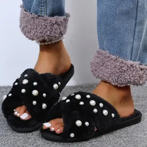 Close-up of black fluffy slippers with pearl accents and cross strap design
