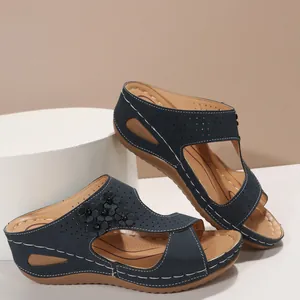 Detail view of navy blue wedge sandals with flower applique and perforated design