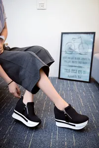 Elegantes zapatillas casuales negras con plataforma y cremallera lateral en modelo.