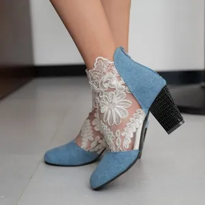 Close-up of stylish lace mesh and denim high heel boots with floral embroidery detail