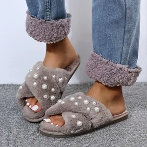 Detailed view of grey fuzzy cross-strap slippers with pearl embellishments on feet