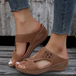 Detail view of women's brown wedge sandals with laser-cut flowers and platform sole.