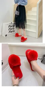 Gros plan sur des chaussons en peluche rouges avec un grand pompon et bout ouvert.
