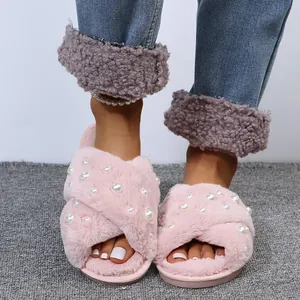 Close-up of pink fuzzy slippers with elegant faux pearl embellishments on criss-cross straps