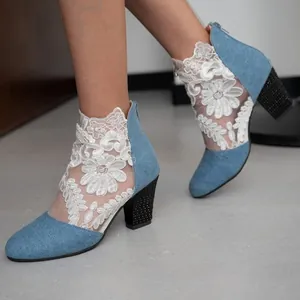 Detail view of denim blue high heel boots with white lace mesh and chunky heels