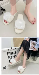 Détail de chaussons en peluche blancs élégants avec de grands pompons portés par un mannequin