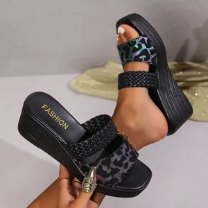 Close-up of stylish black wedge sandals with glittery leopard print and woven straps