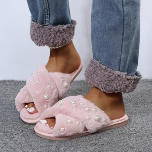Close-up of pink fuzzy slippers with elegant pearl accents and soft cross straps design
