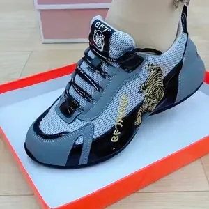 Detailansicht der goldenen Tigerstickerei auf atmungsaktiven grauen und schwarzen Chunky-Sneakern.