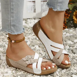 Close-up of women's beige wedge sandals with criss-cross straps and buckle detail