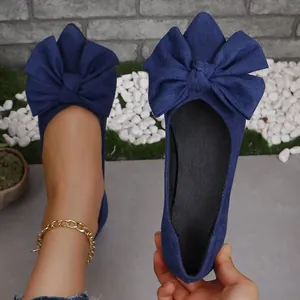 Dettaglio di ballerine a punta in camoscio blu con un fiocco decorativo oversize